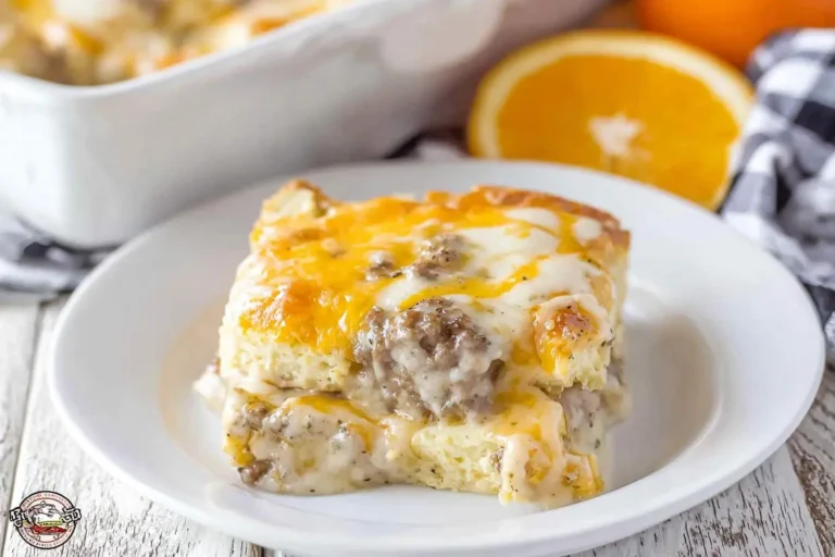 A delicious slice of Biscuits and Gravy Breakfast Casserole with melted cheese, savory sausage, and creamy gravy on a white plate.