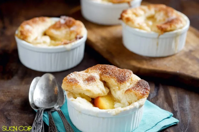 A close-up of delicious baked mini peach cobblers in white ramekins, topped with a golden-brown crust and powdered sugar.