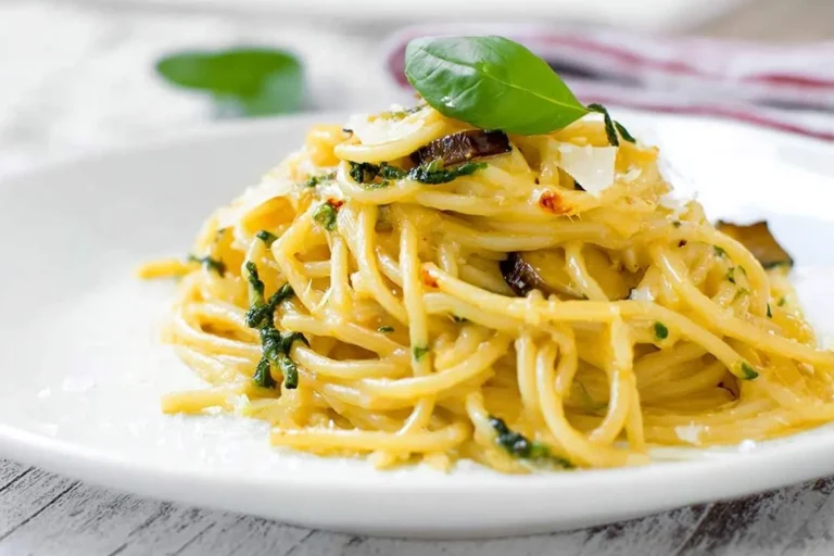 Close-up of a delicious plate of Spaghetti Alla Nerano, featuring golden pasta tossed with zucchini, cheese, and fresh basil.
