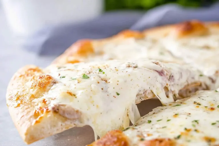 A close-up of a white pizza slice being lifted, revealing strings of melted, gooey cheese, a golden crust, and sprinkled herbs.