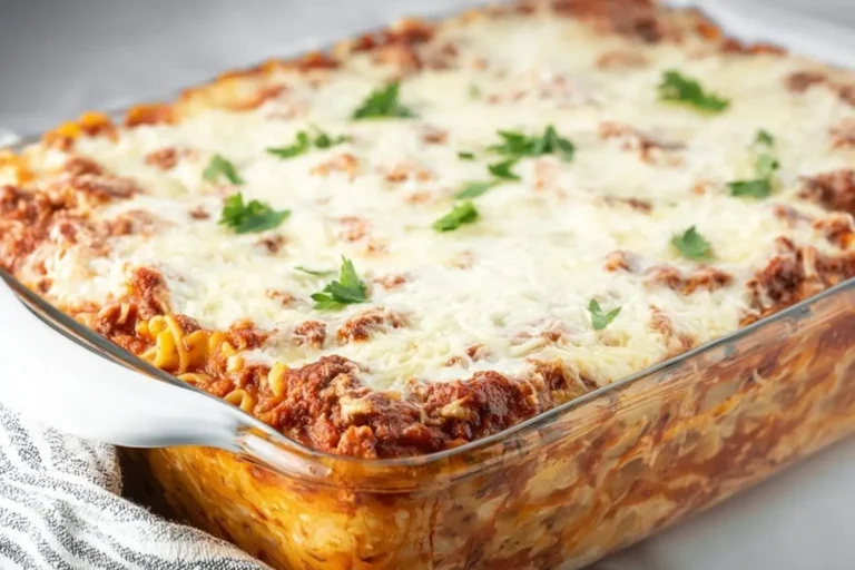 A freshly baked Lasagna Casserole in a clear glass dish, topped with melted mozzarella cheese and fresh parsley garnish.