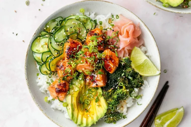 A vibrant salmon rice bowl featuring glazed salmon chunks, sliced cucumber, avocado, roasted broccoli, and pickled ginger over white rice.