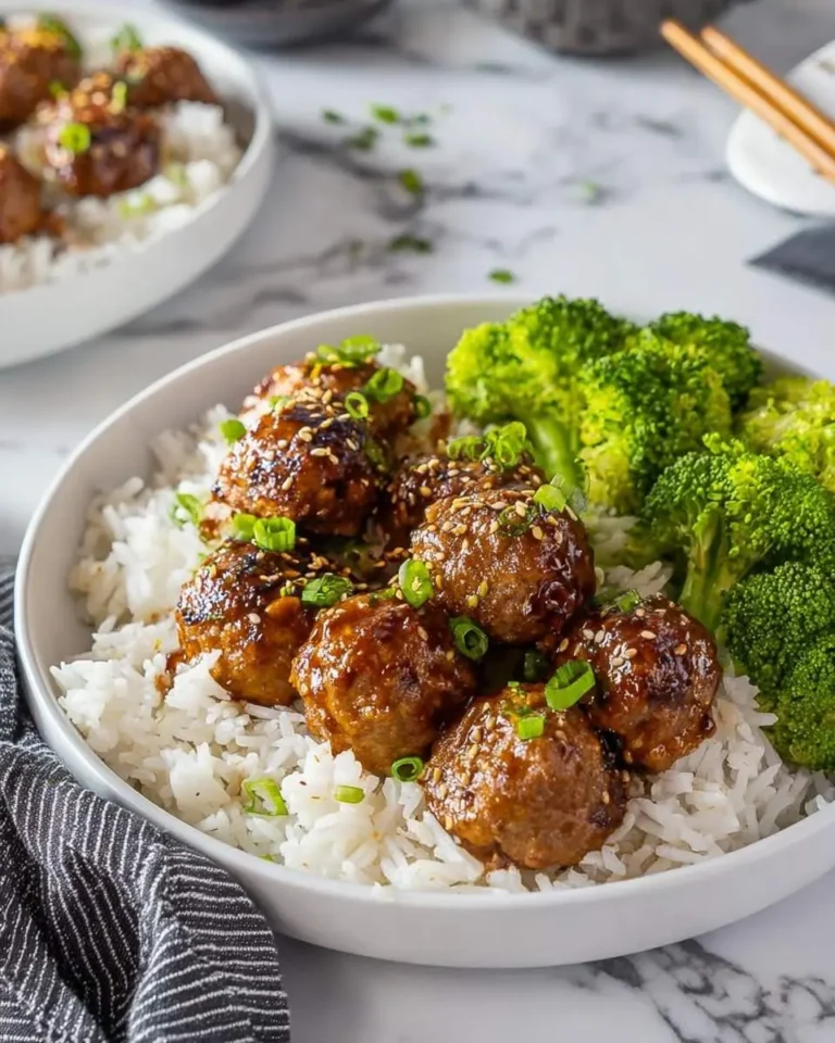 A close-up shot of a white bowl featuring glossy Korean BBQ Meatballs over white rice, garnished with green onions and sesame seeds, alongside bright green steamed broccoli.