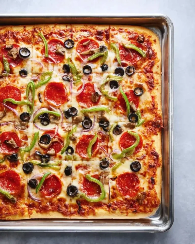 A rectangular Sheet Pan Pizza loaded with pepperoni, black olives, green peppers, red onions, and mushrooms, fresh from the oven.
