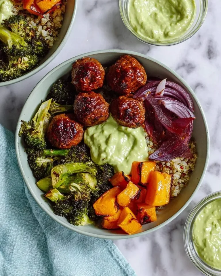 A vibrant Barbecue Meatball Bowl with roasted broccoli, butternut squash, red onion, quinoa, and a creamy green Avocado Sauce, with another sauce dish nearby.