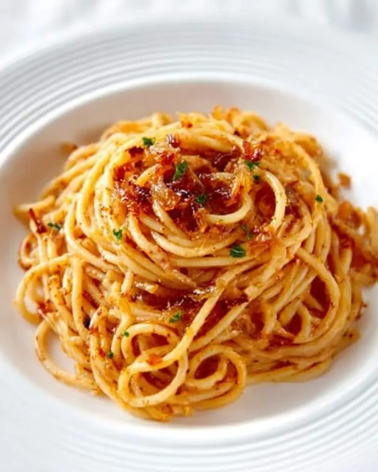 A delightful plate of Caramelized Shallot Pasta, featuring swirled spaghetti generously topped with golden-brown shallots and fresh herbs.