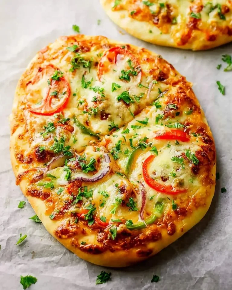 Delicious Naan pizza topped with melted cheese, sliced tomatoes, bell peppers, red onion, and fresh parsley on parchment paper.