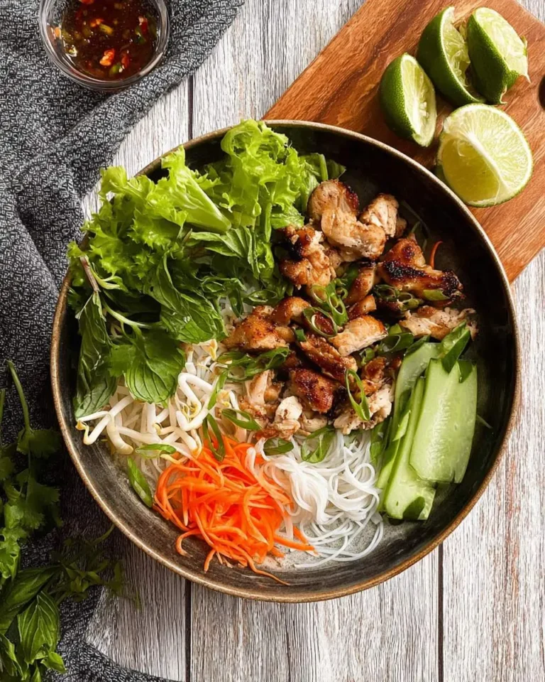 A fresh Vietnamese Noodle Bowl with Chicken, with grilled chicken, rice noodles, lettuce, mint, sprouts, carrots, and cucumber.