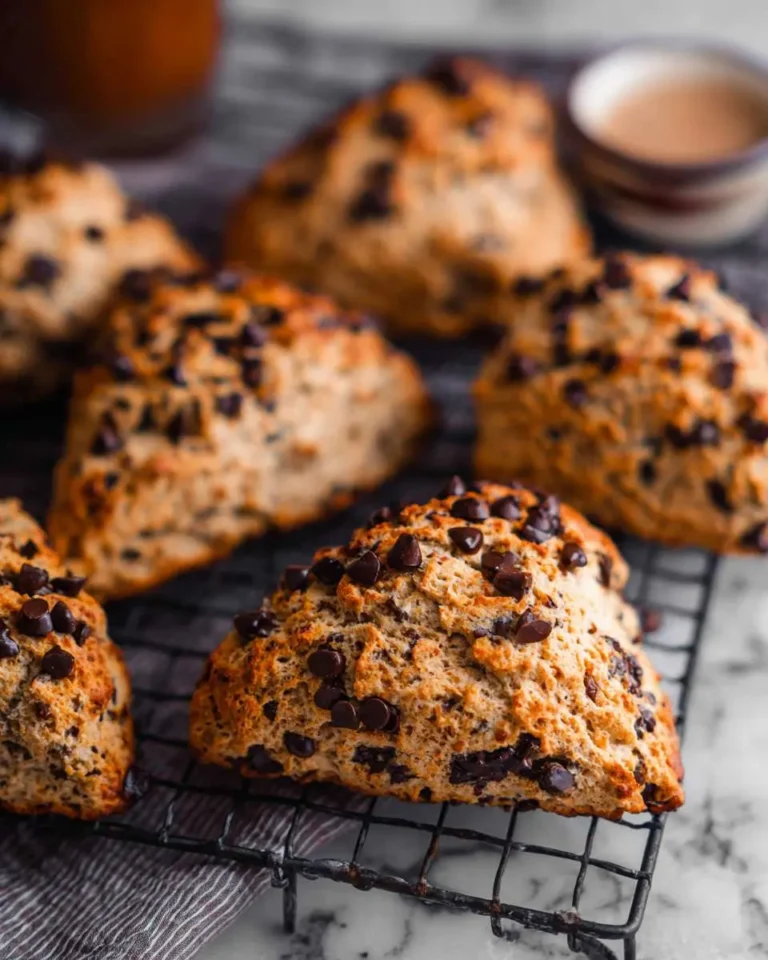 Golden-brown Chocolate Chip Coffee Scones cooling on a wire rack, generously sprinkled with mini chocolate chips.