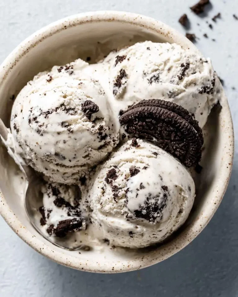 A close-up of a bowl filled with scoops of delicious cookies and cream ice cream, garnished with an Oreo cookie.