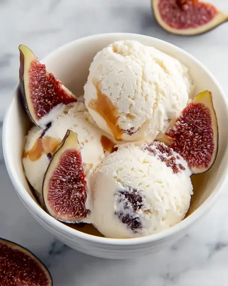 Scoops of creamy fig ricotta ice cream garnished with fresh fig wedges and a caramel drizzle in a white bowl.