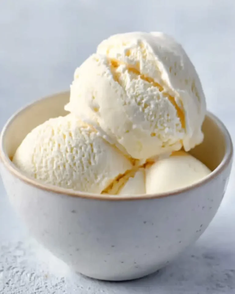 Three creamy scoops of delicious no-churn vanilla ice cream are served in a white speckled bowl.
