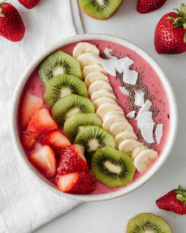 A vibrant Strawberry Kiwi Smoothie Bowl topped with fresh strawberries, sliced kiwi, bananas, coconut flakes, and chia seeds.