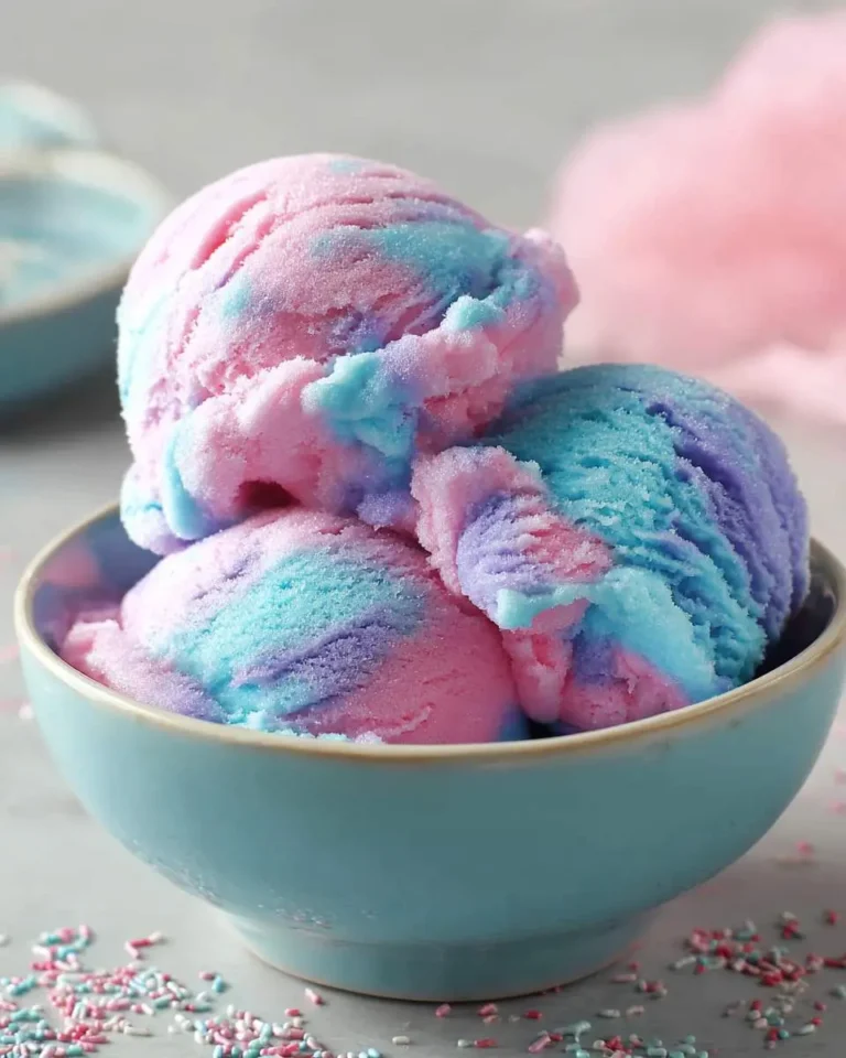 Three scoops of colorful Cotton Candy Ice Cream with pink, blue, and purple swirls in a light blue bowl.