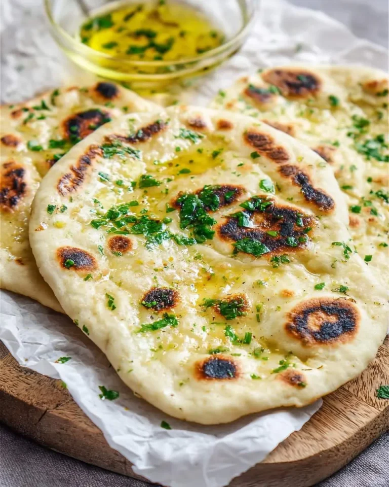 Freshly cooked Garlic Naan Bread topped with melted butter and chopped cilantro, served on a wooden board.