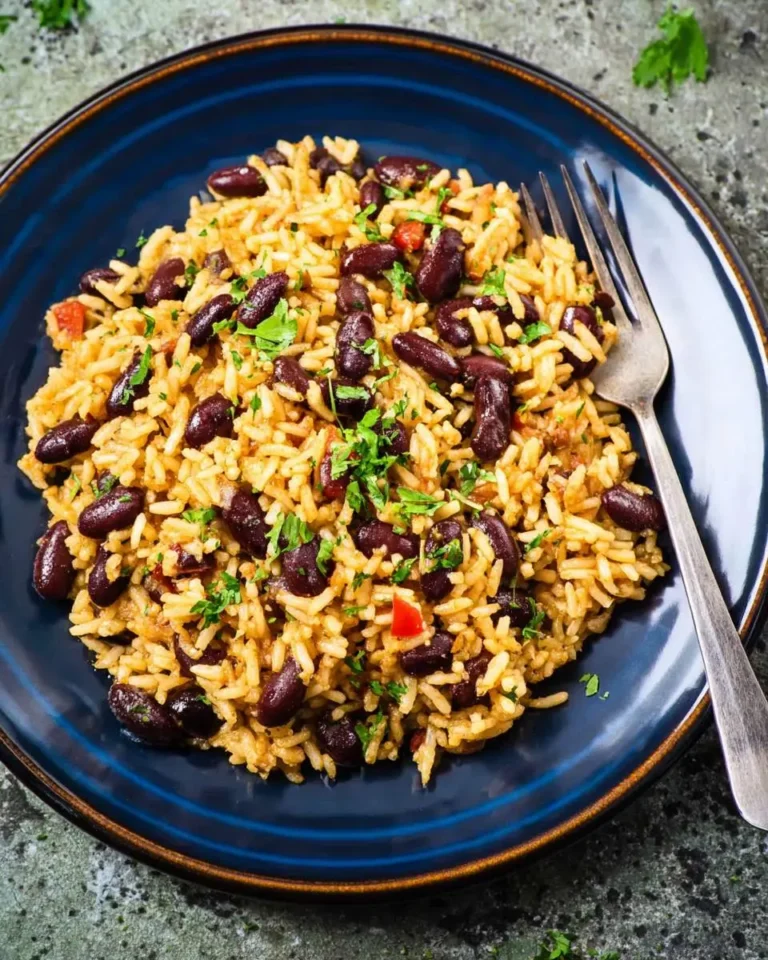Mediterranean rice and beans served on a blue plate with a fork, garnished with fresh herbs.