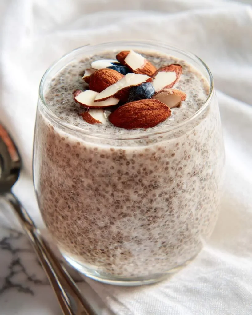 Creamy Chia Pudding with Almond Milk topped with sliced almonds and blueberries in a glass jar.