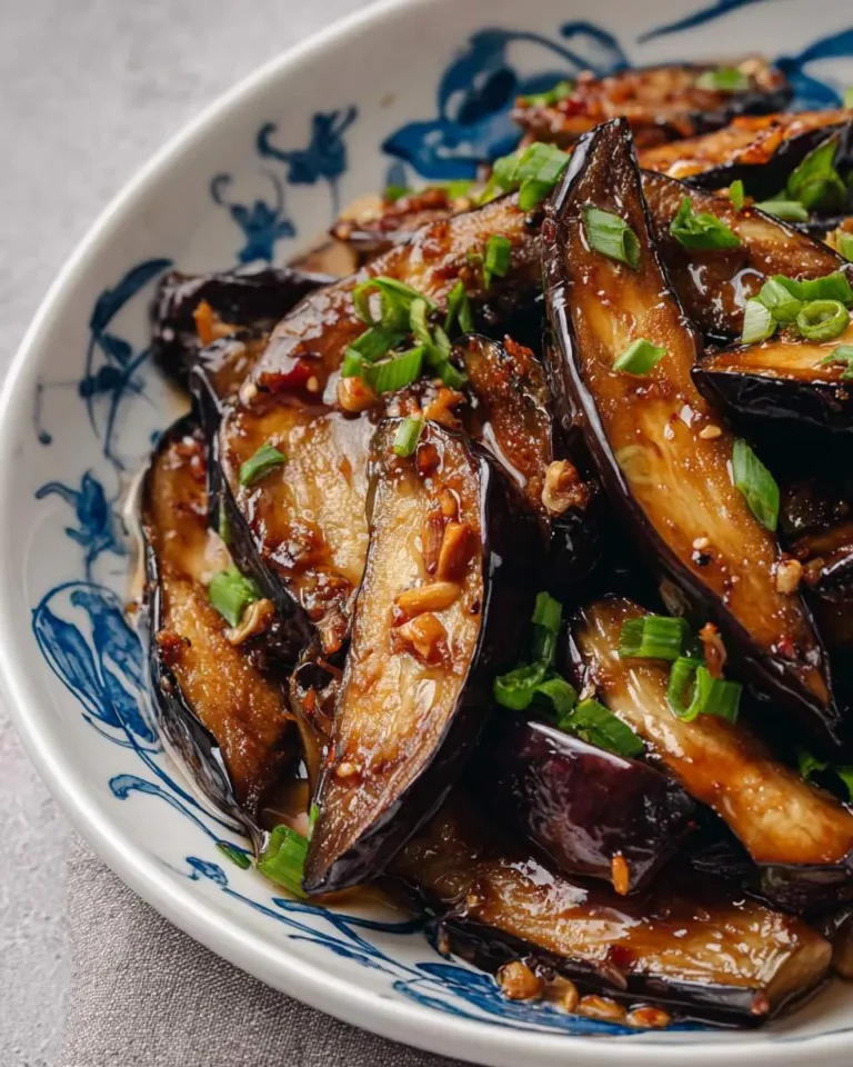 Chinese Eggplant with Garlic Sauce served in a blue and white patterned bowl, garnished with chopped green onions.