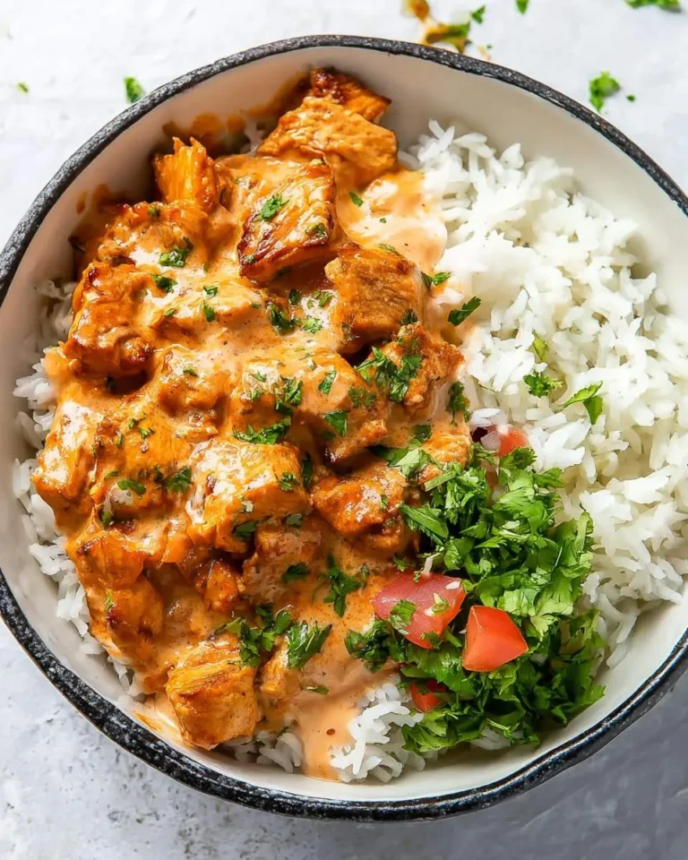 Coconut Chicken Rice Bowl with creamy orange chicken, white rice, and fresh cilantro in a black rimmed bowl.