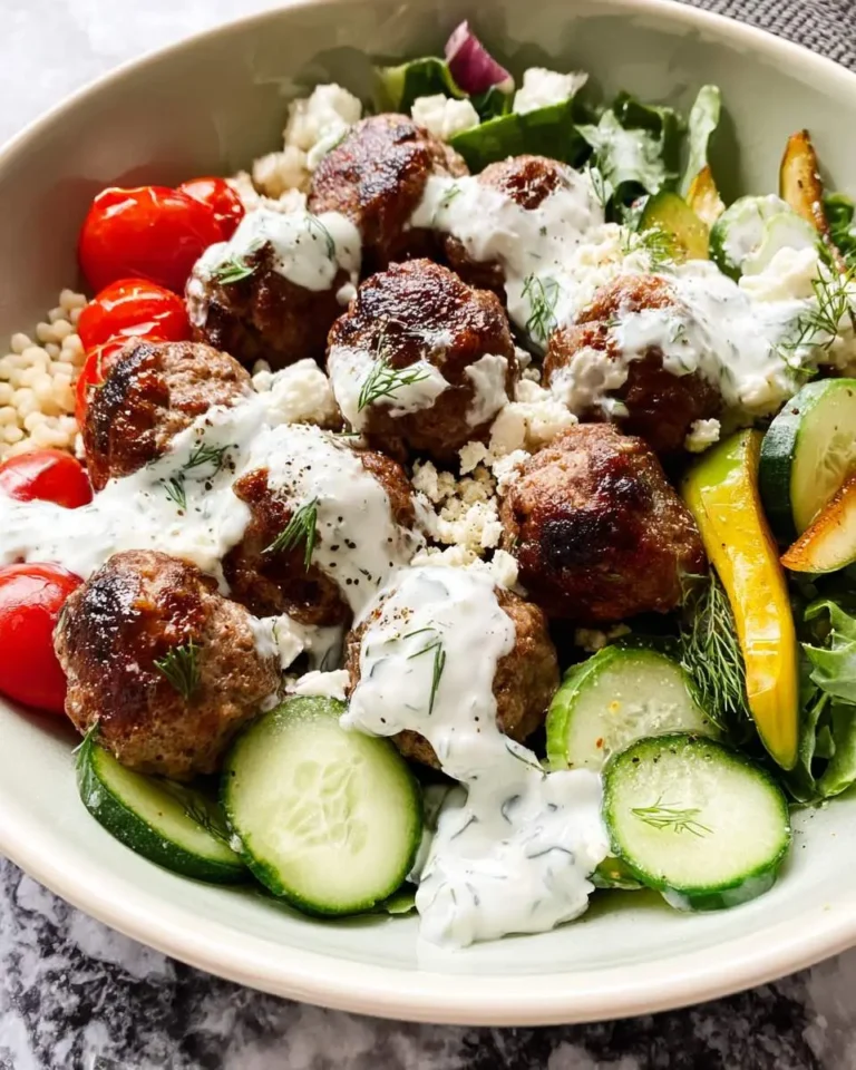 Greek Meatball Bowl with Tzatziki featuring seasoned meatballs, fresh cucumbers, tomatoes, and creamy yogurt sauce over greens.