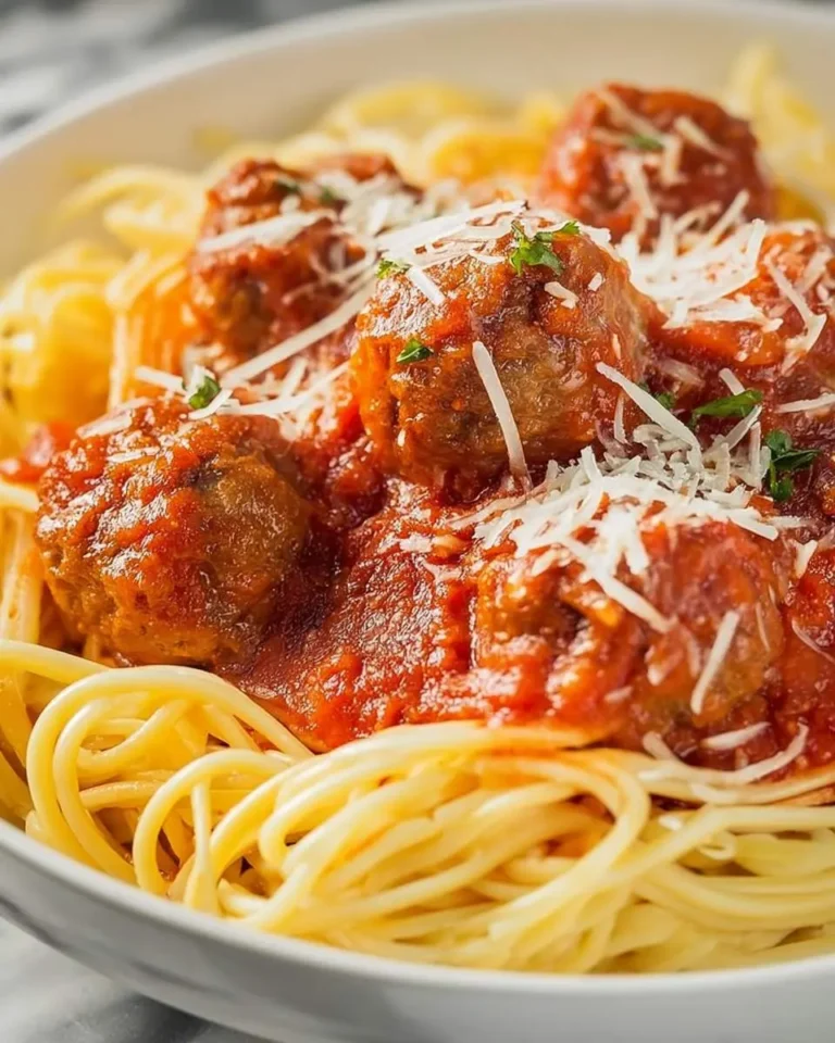 Italian Meatballs on Parmesan Noodles served in a white bowl with marinara sauce and fresh herbs.