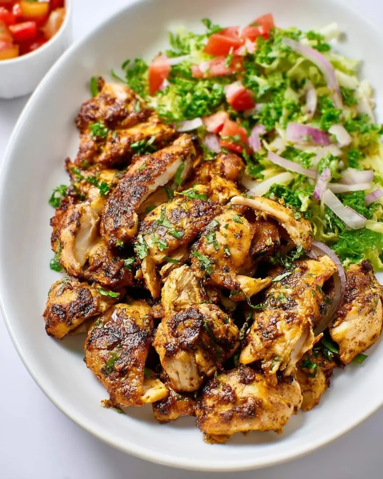 A white plate filled with sliced Keto Chipotle Chicken served alongside a fresh green salad with tomatoes and red onions.