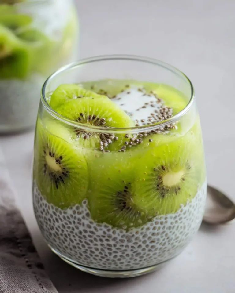 A glass of kiwi chia pudding layered with creamy chia seeds and fresh kiwi slices, topped with additional chia seeds.