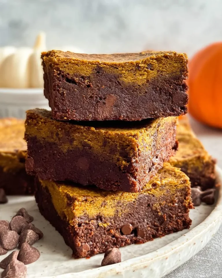 Stack of three low calorie pumpkin brownies with chocolate chips on a white plate.