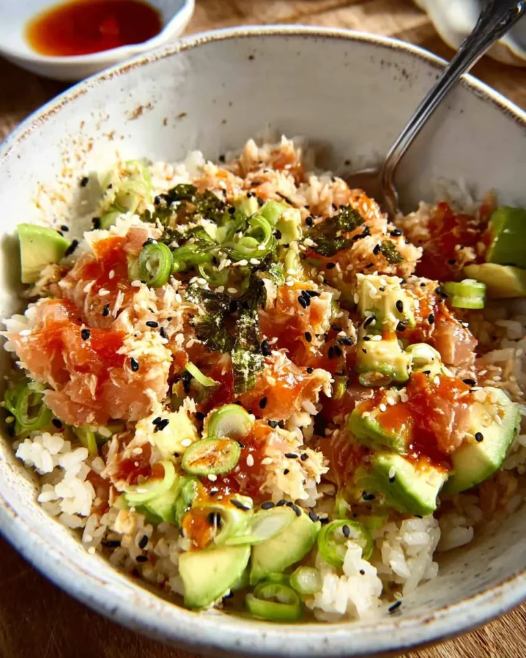 A low carb spicy tuna rice bowl topped with avocado, green onions, sesame seeds, and nori in a ceramic bowl.