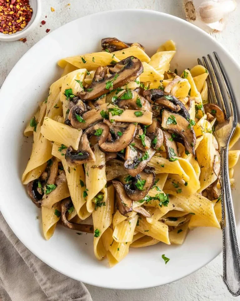 Creamy pasta with portobello mushroom slices garnished with fresh parsley in a white bowl.