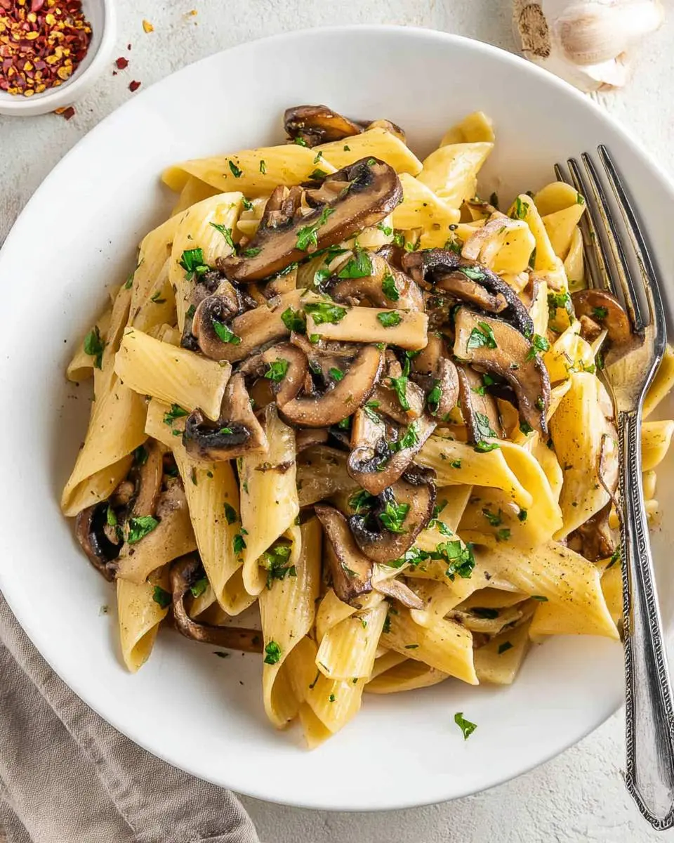 Creamy pasta with portobello mushroom slices garnished with fresh parsley in a white bowl.