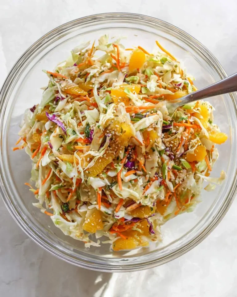 Sesame Orange Napa Cabbage Salad in a glass bowl with shredded vegetables, mandarin oranges, and sesame seeds.
