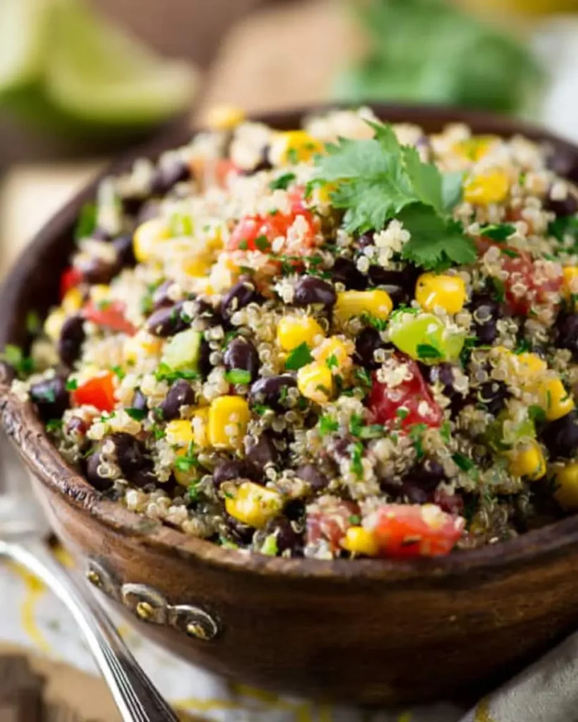 A colorful zesty black bean and corn quinoa salad served in a rustic wooden bowl, garnished with fresh cilantro.