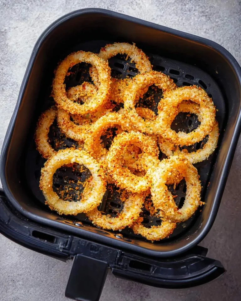 Golden crispy air fryer onion rings arranged in a black air fryer basket, ready to serve.