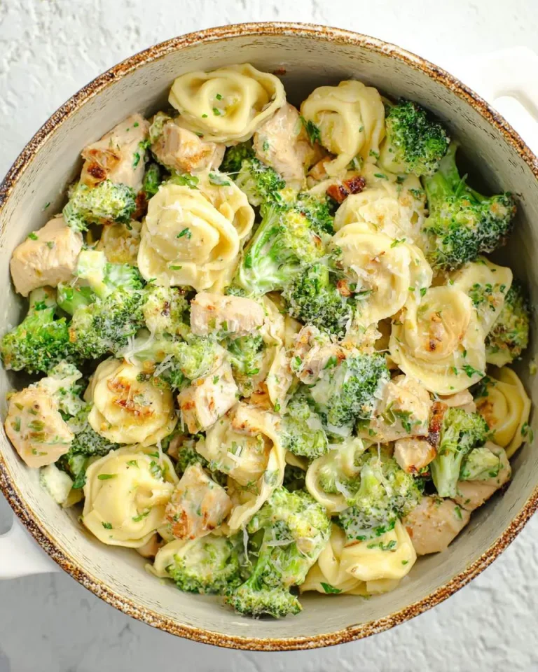 Creamy Chicken Broccoli Tortellini in a rustic pot with parmesan cheese and herbs.