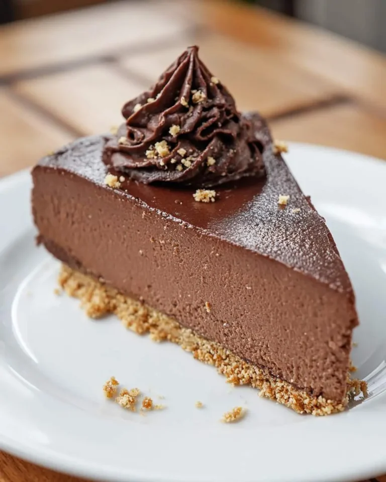 A slice of creamy No Bake Chocolate Cheesecake with chocolate ganache topping and graham cracker crust on a white plate.
