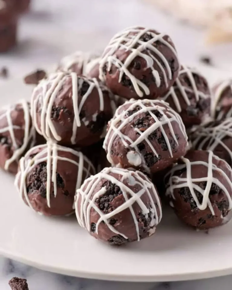 A stack of No Bake Oreo Balls drizzled with white chocolate on a white plate.
