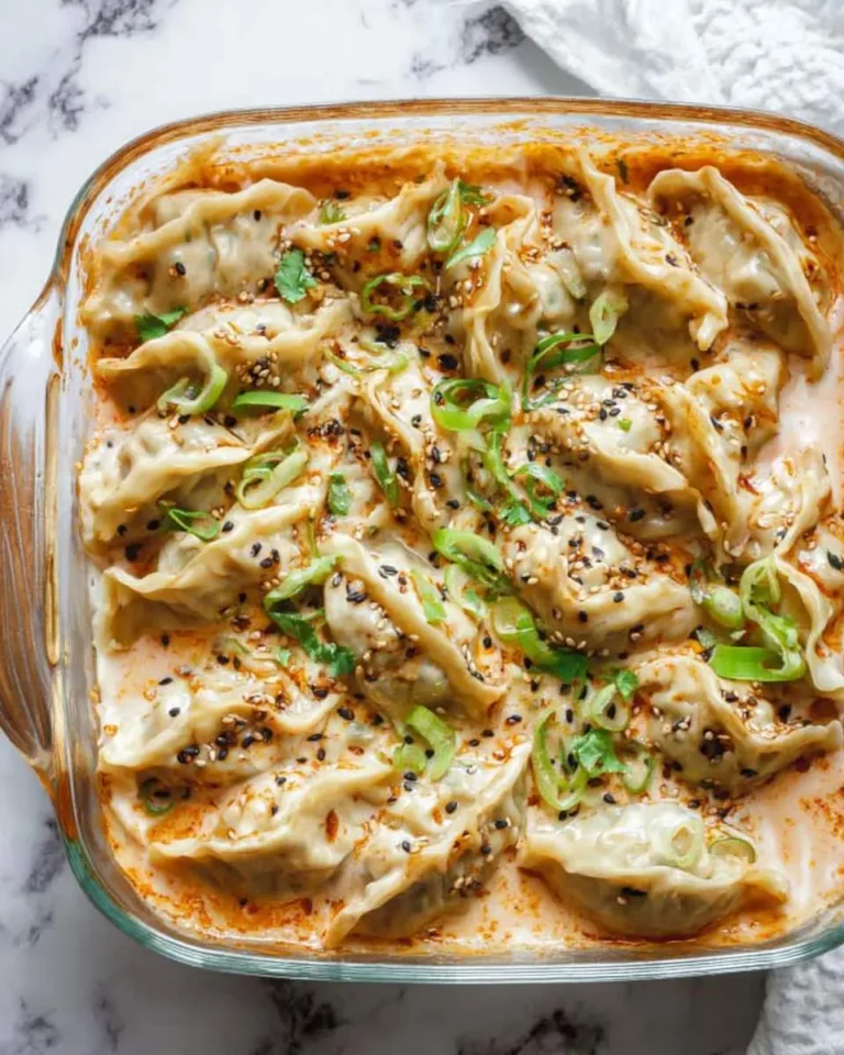 A glass baking dish filled with one pan dumpling bake topped with green onions and sesame seeds.