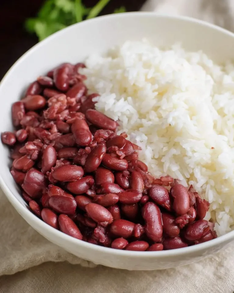A white bowl filled with Red Beans and Rice, featuring cooked red kidney beans and fluffy white rice side by side.