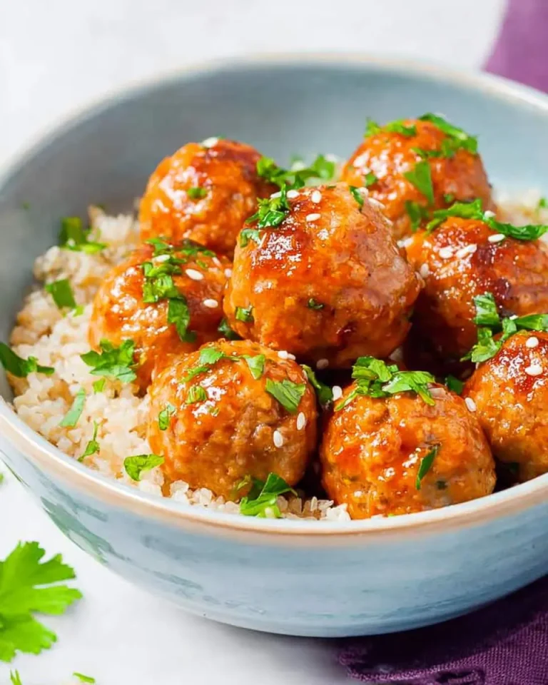 Soy Honey Salmon Meatballs Recipe served over rice in a blue bowl, garnished with fresh herbs and sesame seeds.