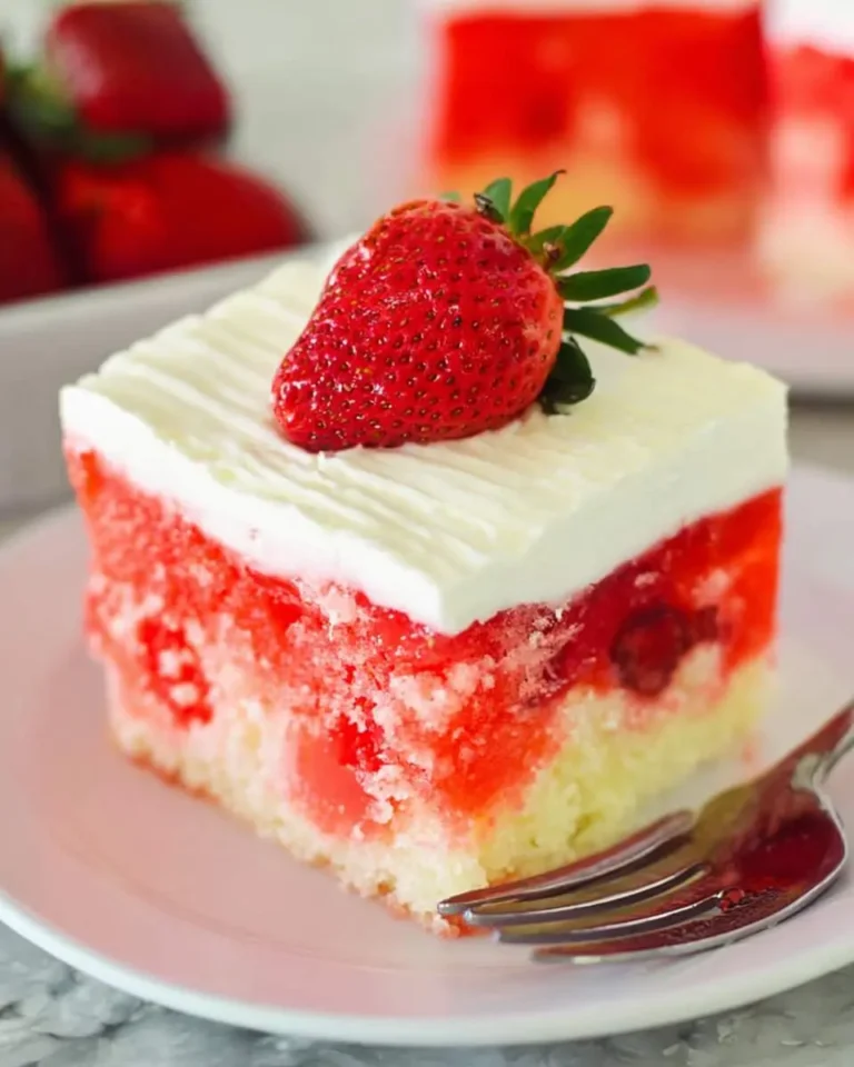 A slice of Strawberry Jello Poke Cake with white frosting and a fresh strawberry on top.