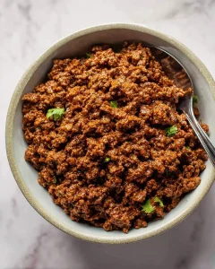 A bowl of seasoned taco meat recipe garnished with fresh cilantro, ready to serve.