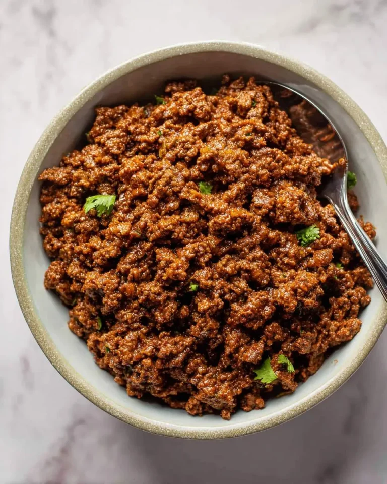 A bowl of seasoned taco meat recipe garnished with fresh cilantro, ready to serve.