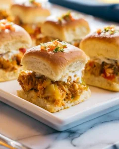 Chicken Fajita Sliders on a white plate topped with colorful peppers and herbs.