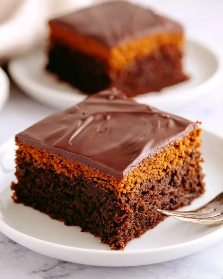 A slice of Chocolate Pumpkin Cake with rich chocolate frosting on a white plate, showing moist layers of chocolate and pumpkin cake.