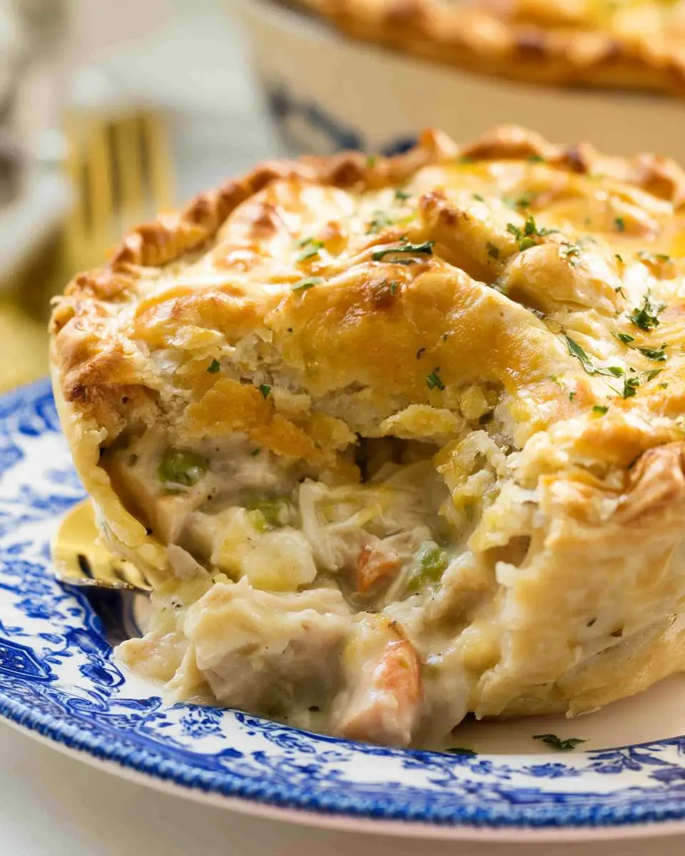 A golden, flaky Turkey Pot Pie Recipe with creamy filling and vegetables served on a blue and white plate.